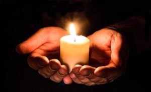 Two hands holding a candle